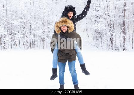 Portrait of happy young couple in winter park with their friend behind Stock Photo