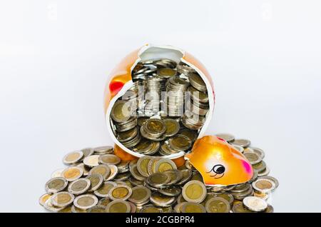 Broken piggy bank with Thai baht coins on white background. Stock Photo