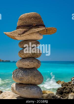 Straw Sunhat at the beach on balanced stones Stock Photo