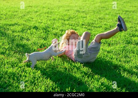 Kid with pets puppy. Portrait of a little cute boy child with dog relaxing on nature. Stock Photo