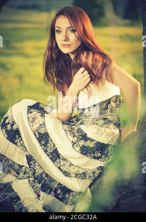 young redhead woman portrait at spring sunset farmland background Stock Photo