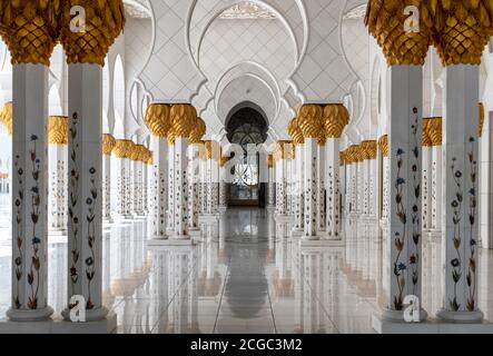 A day shot from inside the archway inside the  Sheikh Zayed Grand Mosque, Abu Dhabi. This includes its architectural features of marble columns with marble floral design and date palm capitals. Mosque completed 2007. Stock Photo