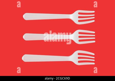 three plastic white forks on a red background Stock Photo