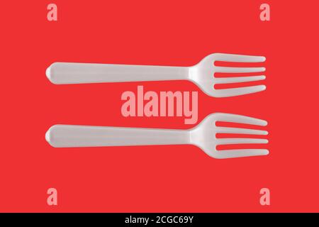 Two plastic white forks on a red background Stock Photo