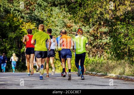 group of male runners running marathon race in autumn park Stock Photo