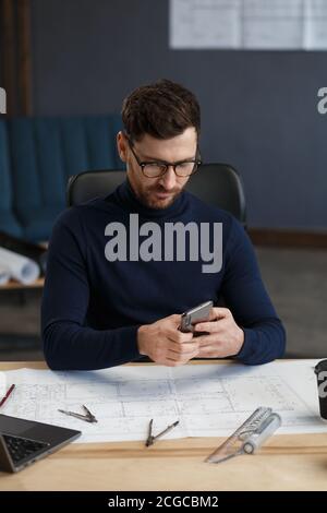 Young man using smartphone and smiling. Happy businessman using mobile phone apps, texting message, browsing internet, looking at smartphone. Concept Stock Photo