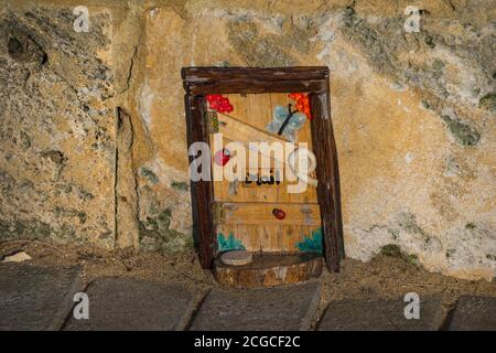 Mandurah, Western Australia - August, 2020: Installation of beautiful tiny wooden handmade door with decoration and mail sign on a limestone wall back Stock Photo