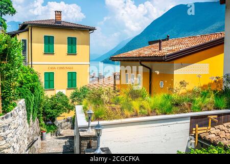 Colorful houses and Gandria town hall or casa comunale and Lake Lugano in background on summer day in Gandria Ticino Switzerland Stock Photo
