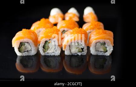 Salmon sushi set. Sushi roll Philadelphia with red fish, salmon, red caviar. Roll with soft avocado and cream cheese under a layer of massago caviar Stock Photo