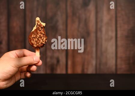 hand holding a half eaten chocolate outer popsicle with melon seeds in a sunny morning Stock Photo