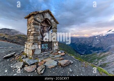 Stelvio pass: aedicule with crucifix in the  Dreisprachenspitze and Mount Ortles in the background. Sondrio province, Lombardy, Italy, Europe. Stock Photo