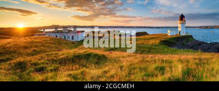 Panoramic view of sunset over the lighthouse and coastguard cottages at Arnish Point in Stornoway harbour on the Isle of Lewis in Scotland