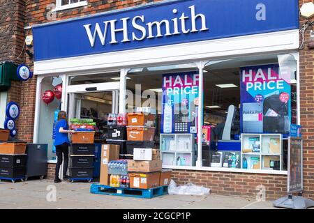 WHSmith female employee pushing goods stock through the entrance door, tenterden, kent, uk Stock Photo