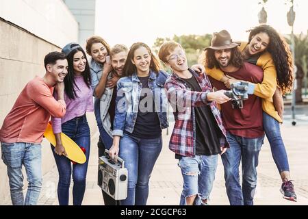 Happy young friends filming video with gimbal mobile smartphone outdoor - Millennial trendy people having fun with new technology social media apps Stock Photo