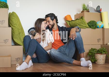 Happy young couple moving in new home first time - Man and woman having fun unpacking carton box in new property house Stock Photo