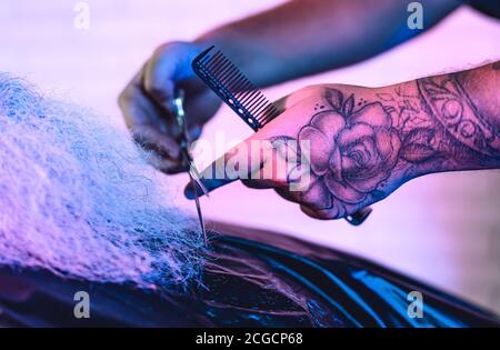 Close up barber tattooed male hands cutting large beard to client - Hairdresser working in barbershop - Hairstylist concept Stock Photo