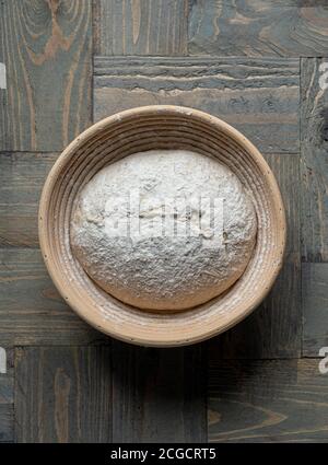 Sourdough bread dough in wicker banneton proving basket on wooden background Stock Photo