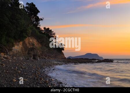 Beautiful sunset over a remote, stony beach on the Coromandel Peninsula, New Zealand Stock Photo