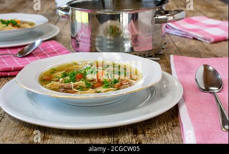 chicken soup dinner table with plate, spoon, pot Stock Photo