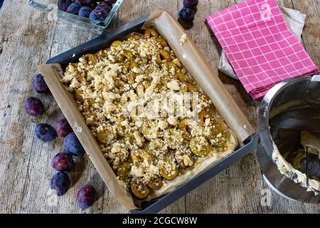 raw and unbaked plum cake on a baking sheet - ready to bake -  one cake with raw crumbles Stock Photo