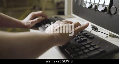 The worker types the machine parameter on the keyboard. Stock Photo