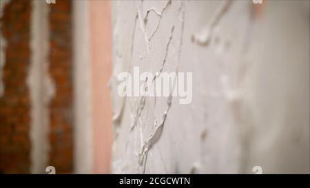 construction notched trowel and worker hands with white mortar on wall. Worker levels a wall with mortar Stock Photo