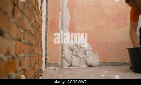 construction notched trowel and worker hands with white mortar on wall. Worker levels a wall with mortar Stock Photo