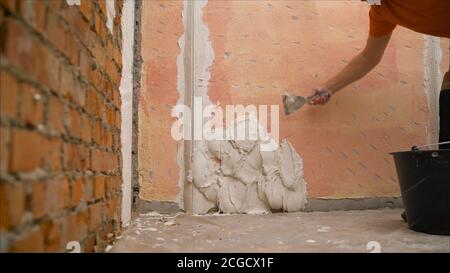 construction notched trowel and worker hands with white mortar on wall. Worker levels a wall with mortar Stock Photo