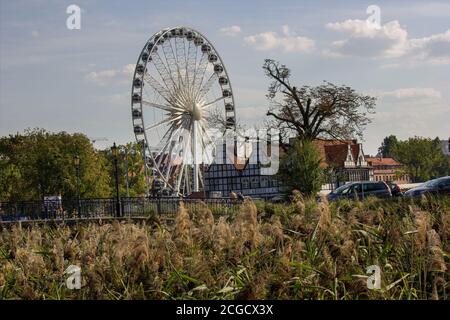 Gdansk, North Poland - August 15, 2020: Ferries wheel agaisnt cloudy sky over motlawa river next to modern building Stock Photo