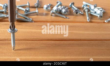 The screwdriver twists the self-cut into wooden boards. Construction tools, home repairs Stock Photo