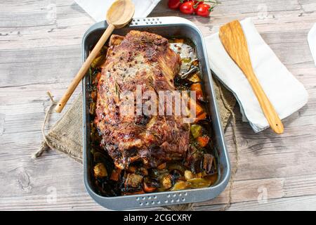 oven baked roast pork - joint of pork on a  baking tray with root vegetables Stock Photo