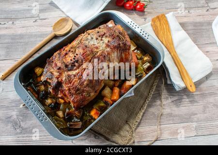 oven baked roast pork - joint of pork on a  baking tray with root vegetables Stock Photo