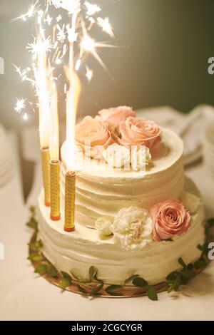 White wedding cake with burning candles at wedding celebration close up Stock Photo