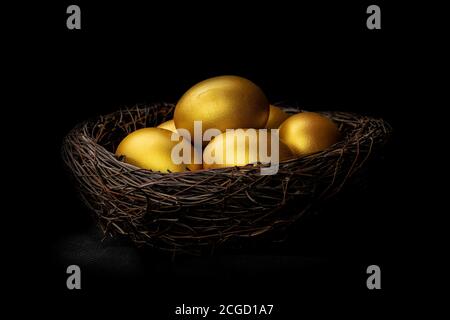 Golden eggs in decorative nest isolated at black background Stock Photo