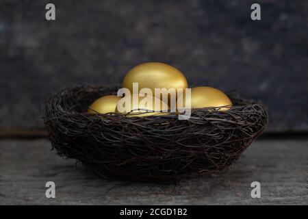 Golden eggs in a nest on the old wood table Stock Photo