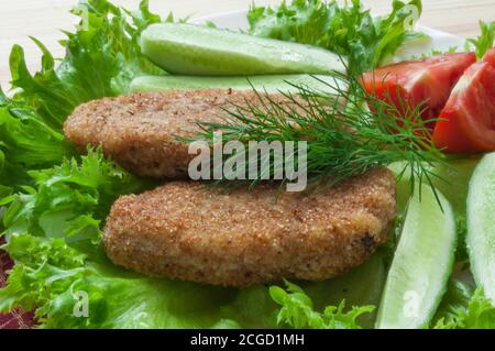 pPortion of potato cutlets on a plate with vegetables (cucumber, tomato) and greens (lettuce, dill). Potato slices, potato cutlets Stock Photo