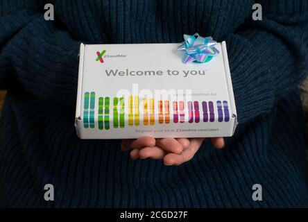 23 and me human DNA testing kit gift with blue gift bow held by two hands. Saliva sampling kit with text Welcome to You. Stock Photo