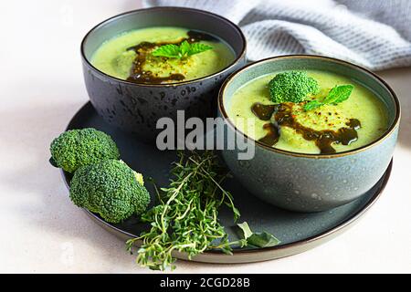 Broccoli or spinach green soup with aromatic spicy oil in bowl. Vegan healthy food. Stone background. Stock Photo