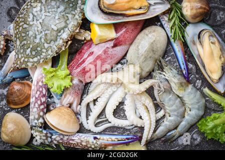 Fresh raw seafood buffet with lemon rosemary ingredients herb and spices / Seafood shellfish on ice frozen with shrimps prawns crab claws shell clam s Stock Photo