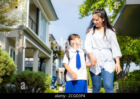 Happy Asian mother and daughter primary school student walking to school in the morning school routine for day in the life getting ready for school. Stock Photo