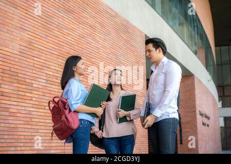Three Asian students are discussing about exam preparation, presentation, study, study for test preparation in University. Education, Learning, Studen Stock Photo
