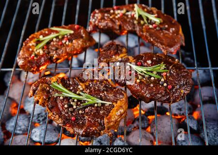Beef steaks on the grill grate with fiery coals. Barbecue, grill and food concept. Stock Photo