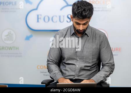 New Delhi, August 28, 2020: Portrait of handsome young Indian businessman working on laptop. Corporate office environment. Stock Photo