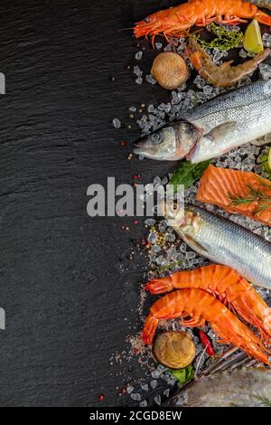 Fresh seafood, mussels, prawns, fish, salmon steak, mackerel and other shells served on black stone Stock Photo