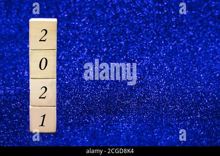 Wooden cubes with numbers 2021 on blue sparkling background. Stock Photo