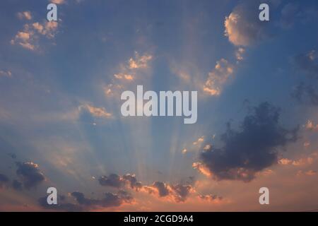 Evening sky. See the sun's rays shining through the clouds and the sky is deep blue. Stock Photo
