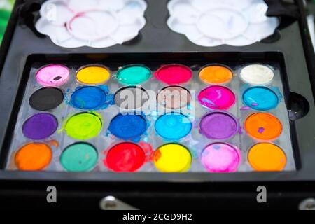 used multicolored watercolor of round shape on a black background,new watercolor paints twenty four colors,watercolors in a black plastic box Stock Photo