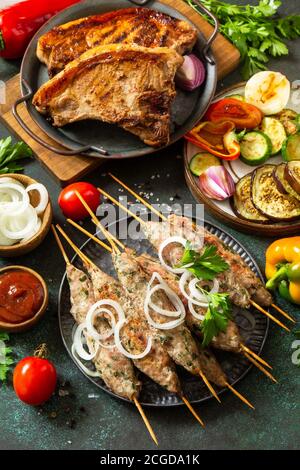 Homemade Kofta kebabs, grilled steak and grilled vegetables on a skewer with vegetables and sauce on a stone or slate background. Stock Photo