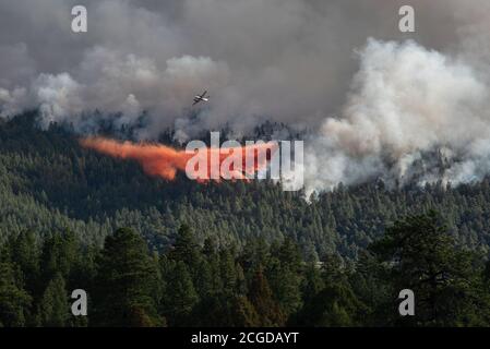 Two planes fly over a forest fire in New Mexico, one spreads retardant as it flies. Stock Photo