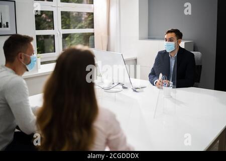 Young Family Couple Meeting Consultant Or Lawyer With Face Masks Stock Photo